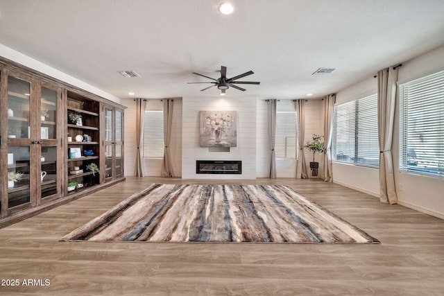 interior space featuring ceiling fan, visible vents, a fireplace, and wood finished floors