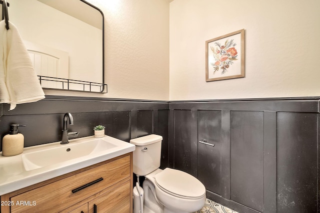 bathroom featuring toilet, vanity, and wainscoting