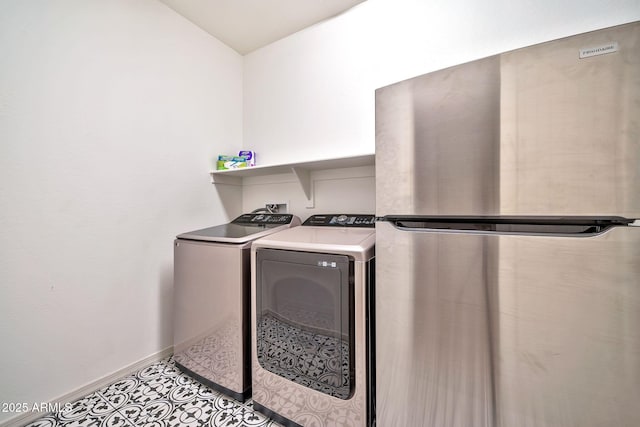 washroom featuring laundry area, baseboards, washer and clothes dryer, and light tile patterned flooring