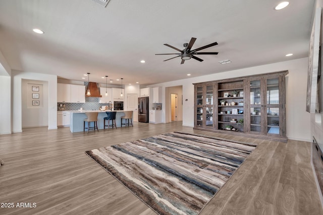 living area with ceiling fan, recessed lighting, baseboards, and light wood-style floors