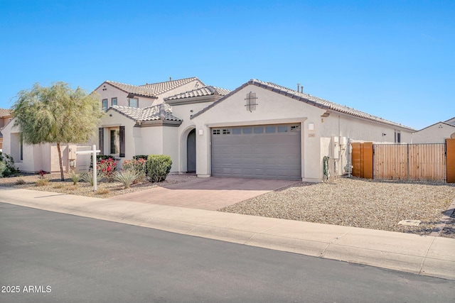 mediterranean / spanish-style home featuring decorative driveway, stucco siding, fence, a garage, and a tiled roof