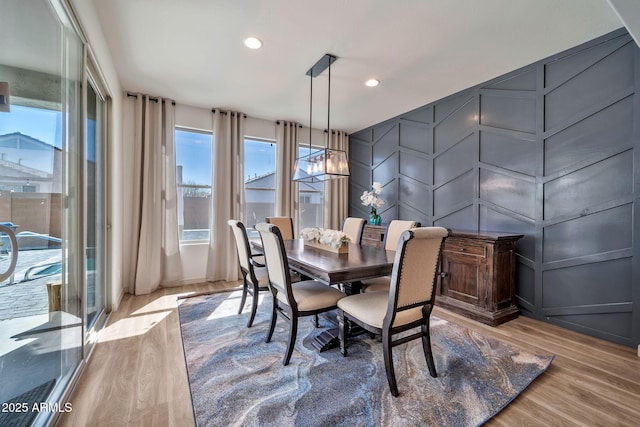 dining area featuring an inviting chandelier, wood finished floors, a wealth of natural light, and a decorative wall