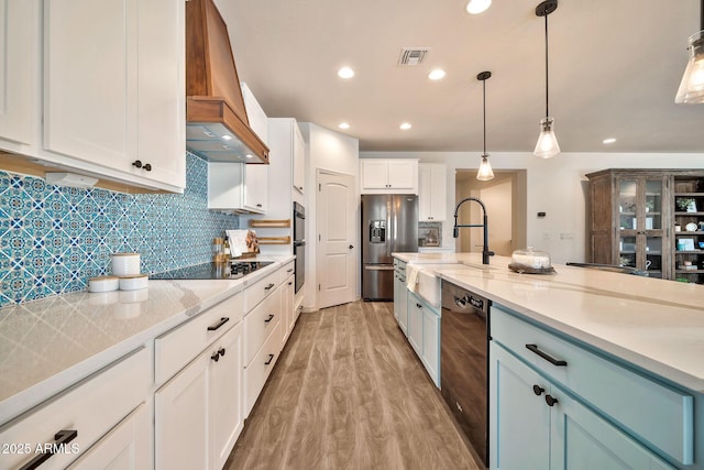 kitchen featuring visible vents, light wood-style floors, white cabinets, premium range hood, and black appliances