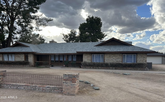 ranch-style home featuring a shingled roof, a chimney, cooling unit, and brick siding