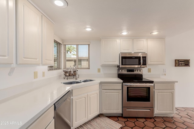 kitchen featuring white cabinets, light countertops, stainless steel appliances, a sink, and recessed lighting