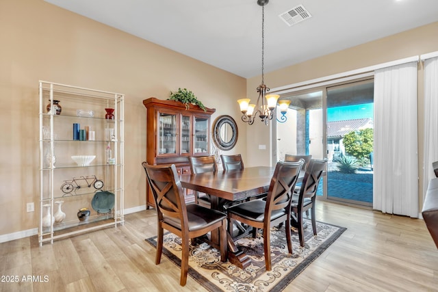 dining area with visible vents, baseboards, a chandelier, and light wood finished floors