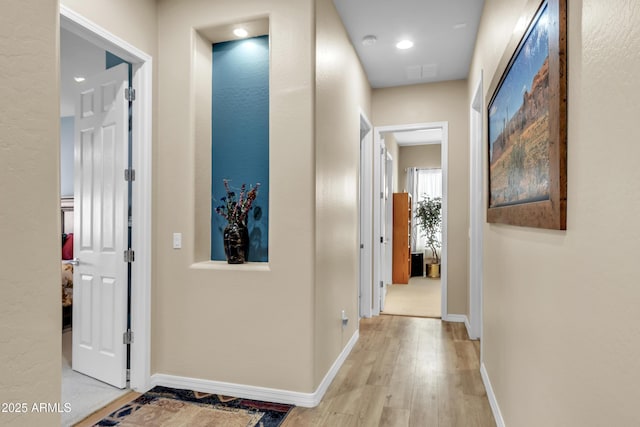 hallway featuring visible vents, baseboards, and light wood-style floors