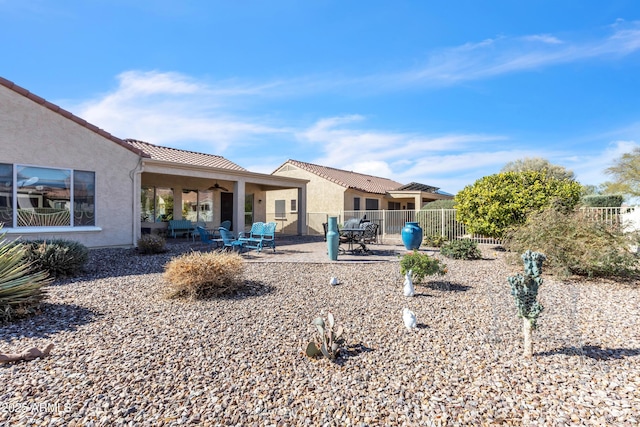 rear view of house featuring a patio, a tiled roof, fence, and stucco siding