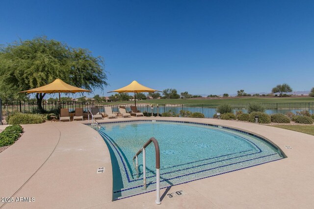 community pool featuring a patio area, a water view, and fence