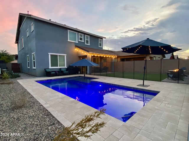 pool at dusk featuring a patio