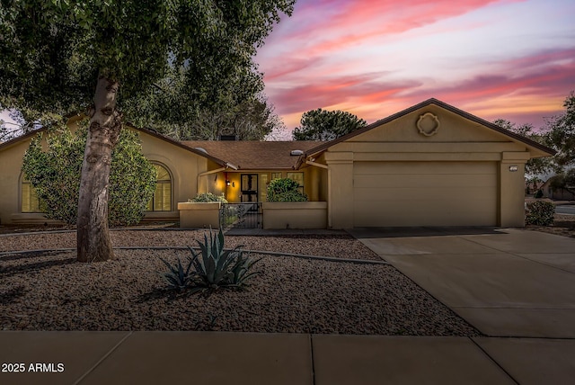 view of front of home featuring driveway, an attached garage, and stucco siding