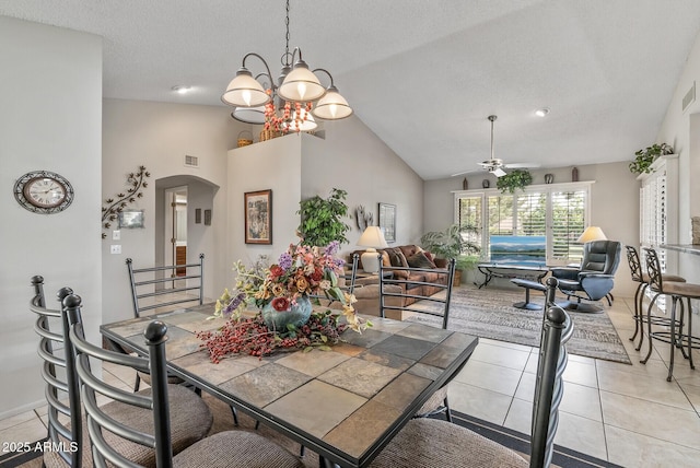 dining space featuring arched walkways, light tile patterned floors, visible vents, high vaulted ceiling, and ceiling fan with notable chandelier