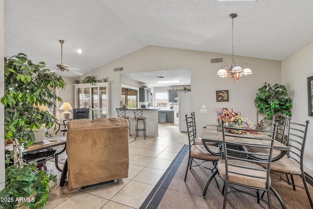 dining room with vaulted ceiling, ceiling fan with notable chandelier, light tile patterned flooring, and visible vents