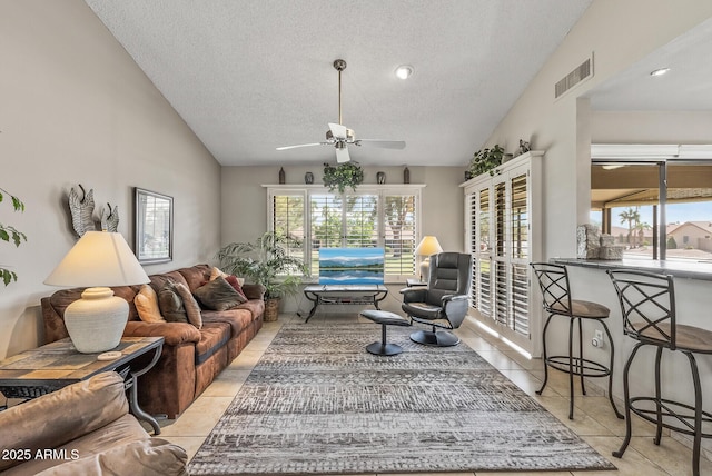 living area with lofted ceiling, a textured ceiling, tile patterned flooring, and visible vents