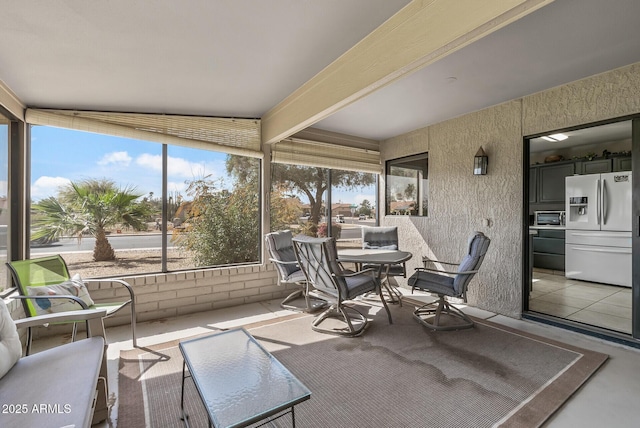 sunroom featuring a toaster and beamed ceiling