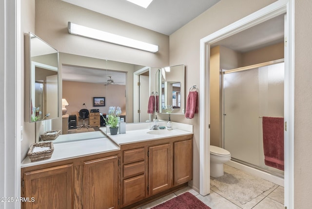 bathroom with a stall shower, toilet, ceiling fan, tile patterned floors, and vanity