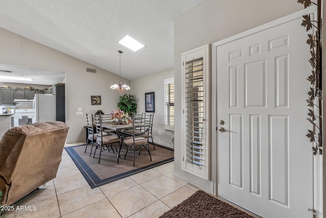 dining room featuring lofted ceiling, visible vents, a textured ceiling, and light tile patterned floors