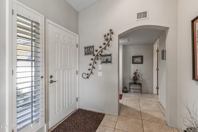 entryway featuring arched walkways, light tile patterned floors, and visible vents