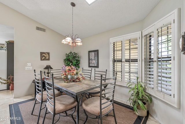 dining space featuring light tile patterned floors, visible vents, an inviting chandelier, vaulted ceiling, and a textured ceiling