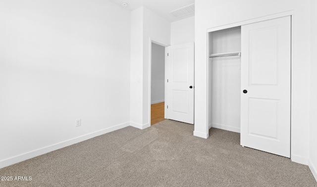 unfurnished bedroom with a closet and light colored carpet