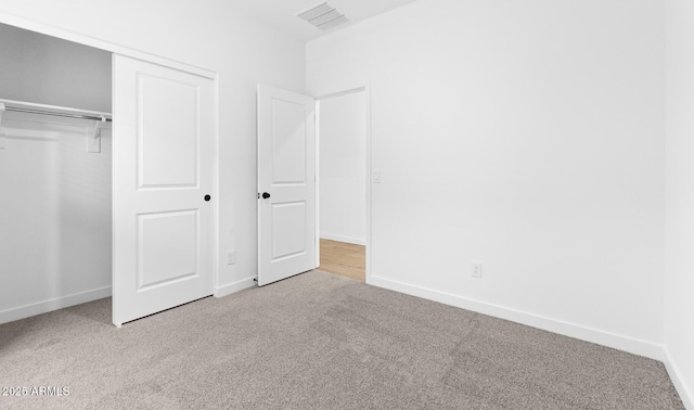 unfurnished bedroom featuring a closet and light colored carpet