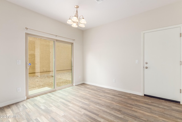 unfurnished room featuring an inviting chandelier and light hardwood / wood-style floors