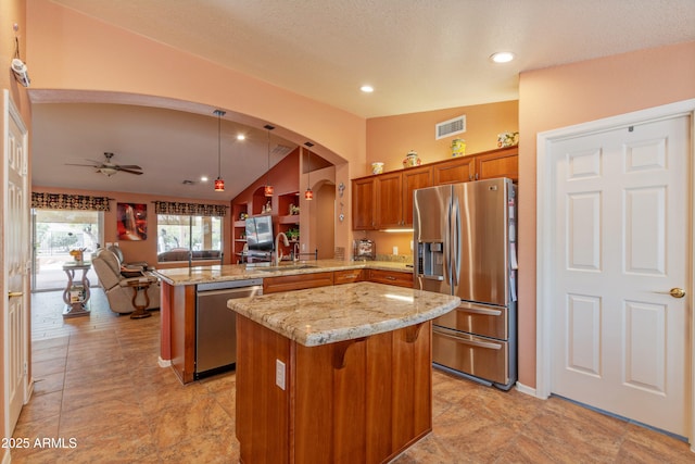 kitchen with visible vents, appliances with stainless steel finishes, brown cabinets, a peninsula, and a sink