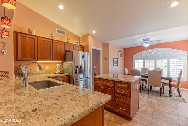 kitchen featuring a sink, visible vents, brown cabinets, a center island, and stainless steel fridge