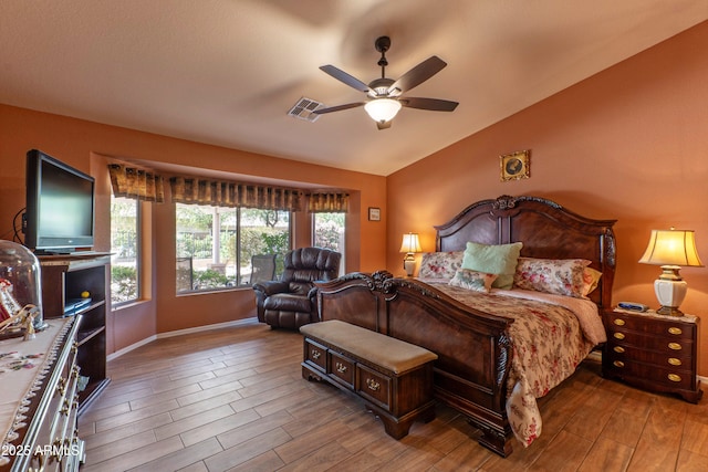 bedroom featuring a ceiling fan, visible vents, vaulted ceiling, and wood finished floors