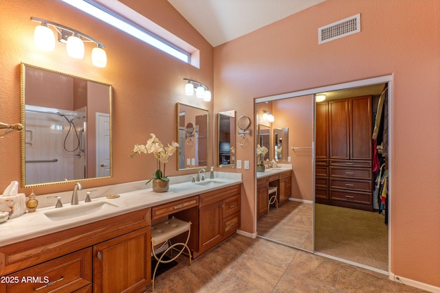 full bath featuring double vanity, visible vents, vaulted ceiling, a sink, and a shower stall