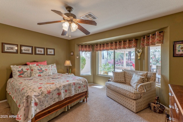 carpeted bedroom featuring a textured ceiling, visible vents, and a ceiling fan