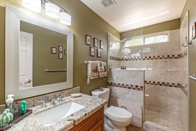 bathroom with a textured ceiling, a textured wall, toilet, visible vents, and walk in shower