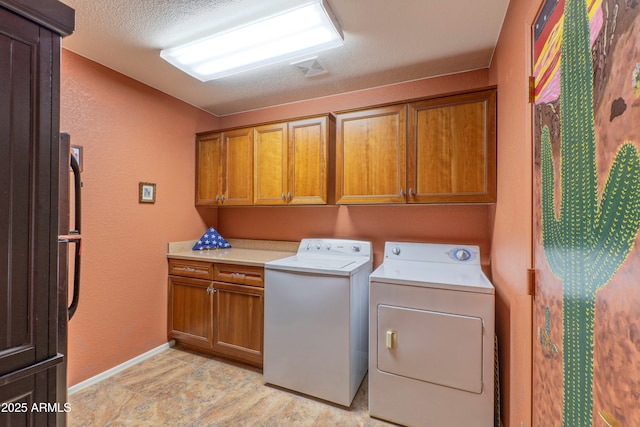 washroom featuring a textured ceiling, baseboards, cabinet space, and washer and dryer