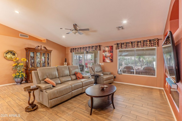 living area featuring lofted ceiling, light wood-style floors, baseboards, and visible vents