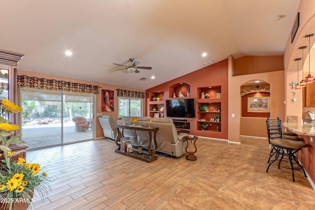 living area featuring lofted ceiling, built in shelves, light wood-style flooring, visible vents, and a ceiling fan