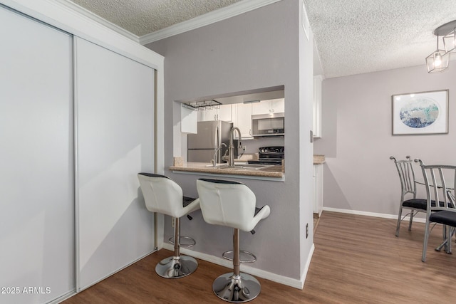 3500 N Hayden Rd Unit 801, Scottsdale, AZ 85251 - kitchen featuring stainless steel appliances, a textured ceiling, wood finished floors, white cabinets, and baseboards