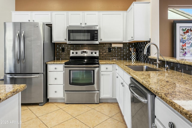 kitchen featuring stainless steel appliances, decorative backsplash, white cabinets, light tile patterned flooring, and sink