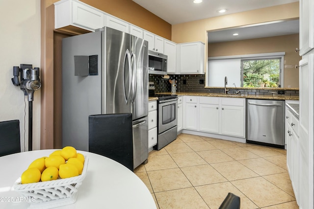 kitchen featuring stone countertops, backsplash, white cabinets, appliances with stainless steel finishes, and sink