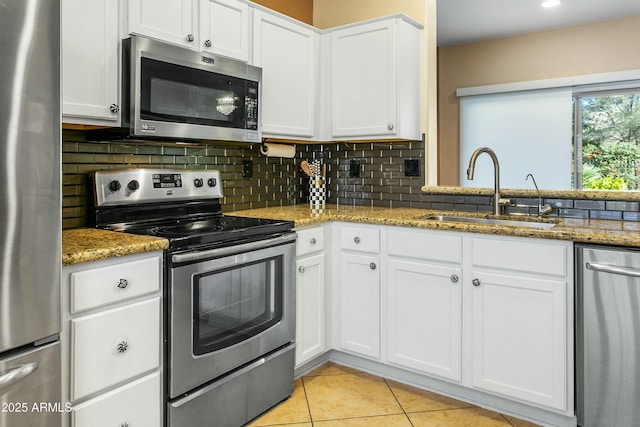 kitchen with light stone countertops, appliances with stainless steel finishes, white cabinetry, and sink