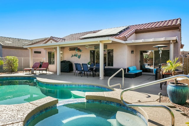 rear view of property with solar panels, ceiling fan, a fenced in pool, and a patio area