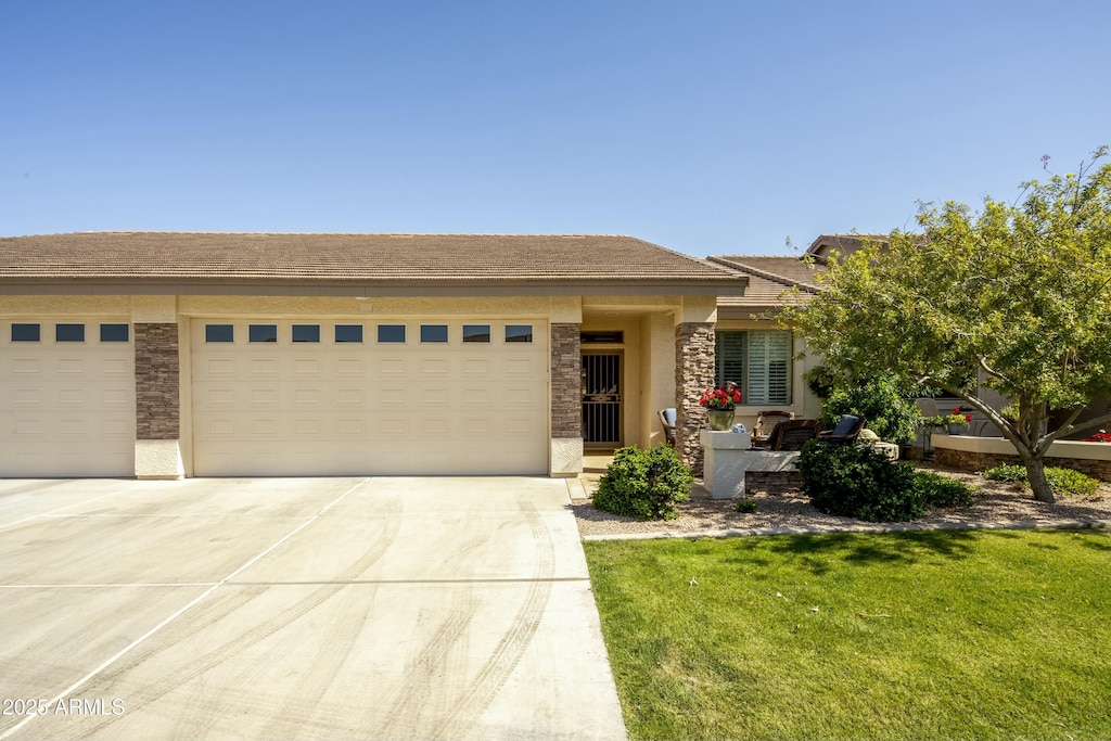 view of front of property featuring concrete driveway, an attached garage, stone siding, and a front lawn