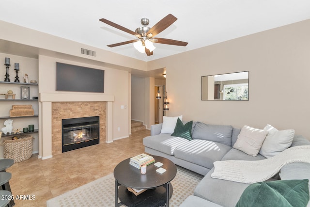 living room featuring ceiling fan and a tiled fireplace