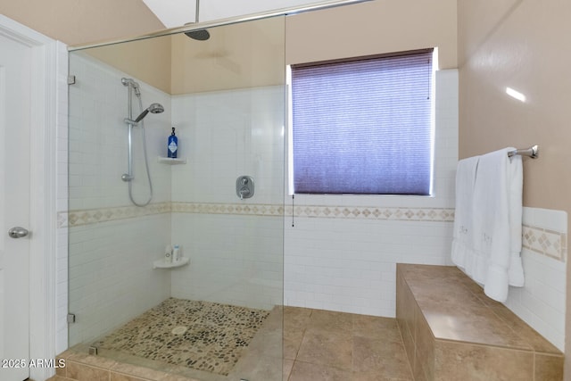 bathroom with tiled shower, tile patterned flooring, and tile walls