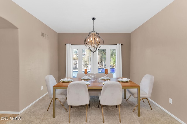 dining room featuring light colored carpet and an inviting chandelier