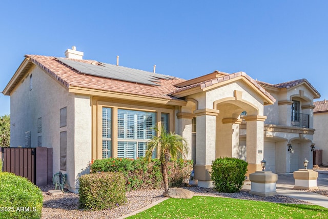 mediterranean / spanish-style home featuring solar panels and a garage