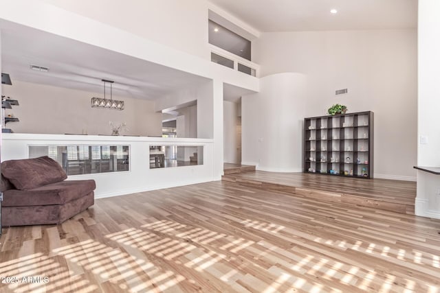 living room featuring hardwood / wood-style floors, a high ceiling, and a chandelier