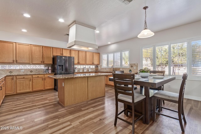 kitchen featuring a center island, stainless steel fridge, wood-type flooring, and hanging light fixtures