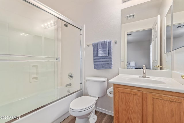 full bathroom with shower / bath combination with glass door, vanity, wood-type flooring, and toilet