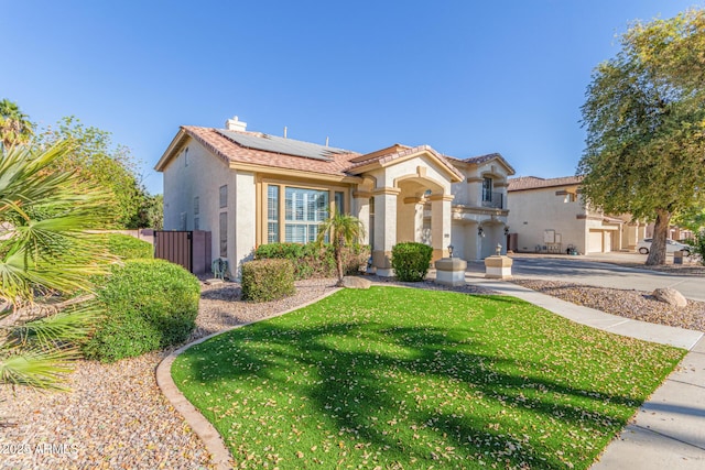 mediterranean / spanish home with a front yard and solar panels