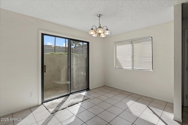 spare room featuring baseboards, a notable chandelier, light tile patterned flooring, and a textured ceiling